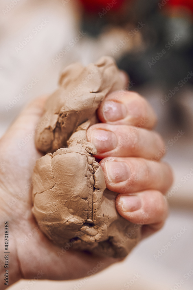 Obraz premium Hand squeezes a piece of clay. Woman preparing clay to make pottery at table in workshop. Handmade Design Art
