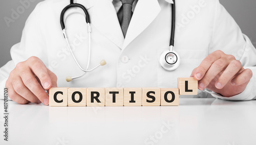 Doctor holds wooden cubes in his hands with text CORTISOL photo