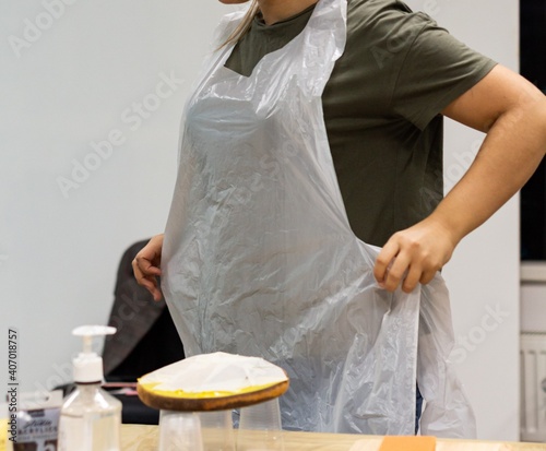 Girl wears disposable apron close-up, hands, table