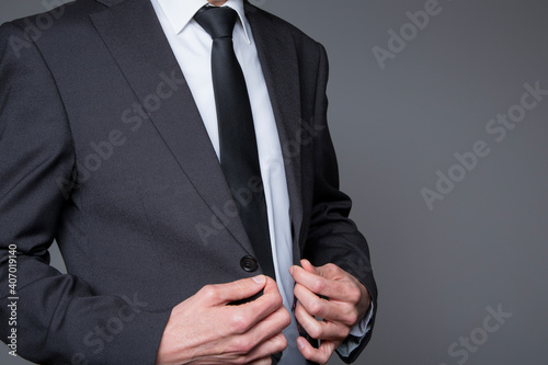 businessman buttoning suit jacket on neutral background
