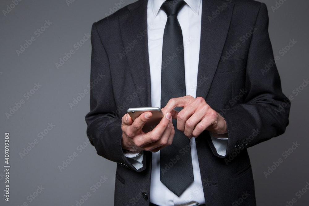businessman in gray suit with mobile phone in hand on gray background businessman in gray suit with mobile phone in hand on gray background