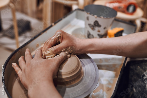 Women working on potters wheel making clay objects in pottery workshop