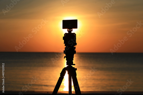 Silhouette video camera against orange sky, vidieo camera shooting sunset or sunrise