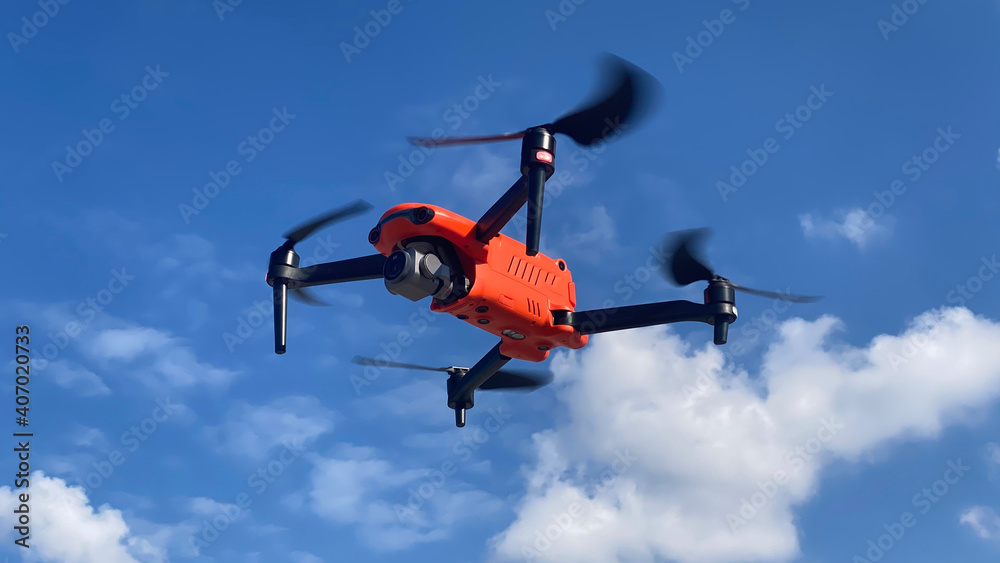 Latest technology RC camera drone or UAV (unmanned aerial vehicle) hovering on deep blue cloudy sky Latest technology RC camera drone or UAV (unmanned aerial vehicle) hovering on deep blue cloudy sky