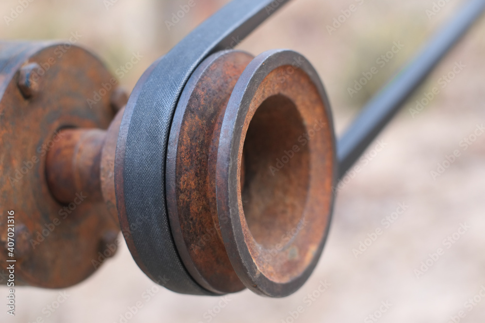 Old rusty flywheel and belt of pump water close up.