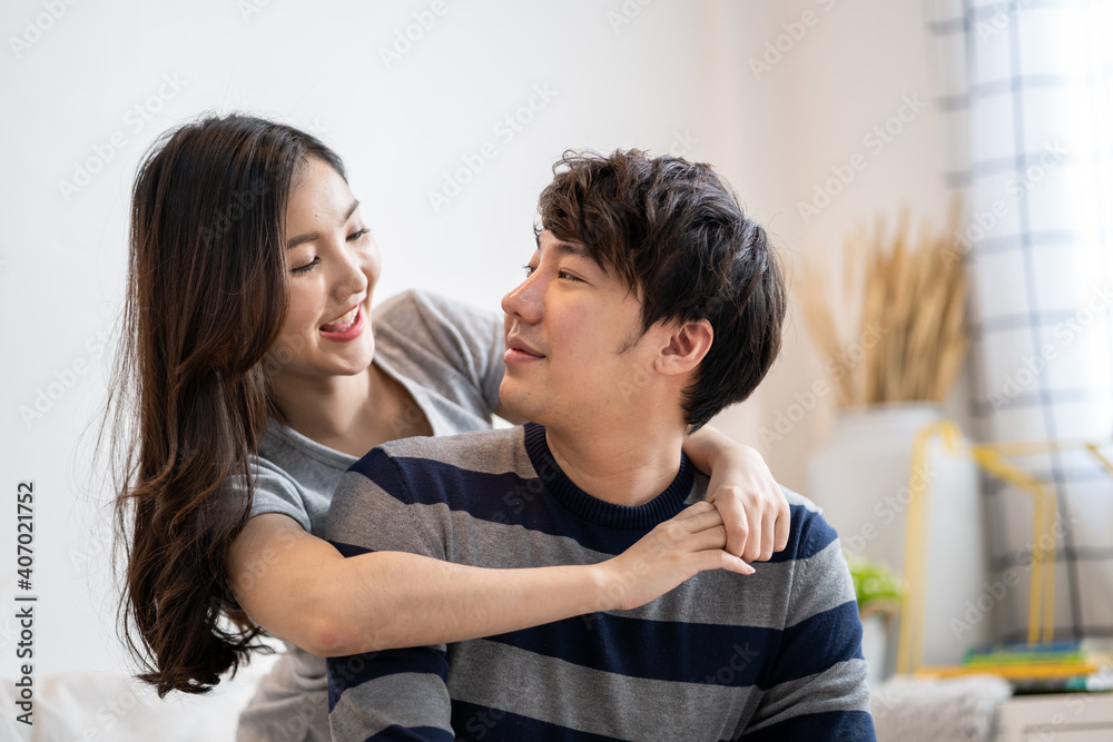 Obraz premium Asian young couples man and woman in bed room. A woman hugging boyfriend from behind, feeling love happiness with smiling Relationship of young woman and man remantic concept