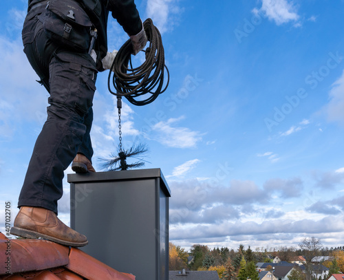 Valokuvatapetti Chimney sweep man in work uniform cleaning chimney on building roof