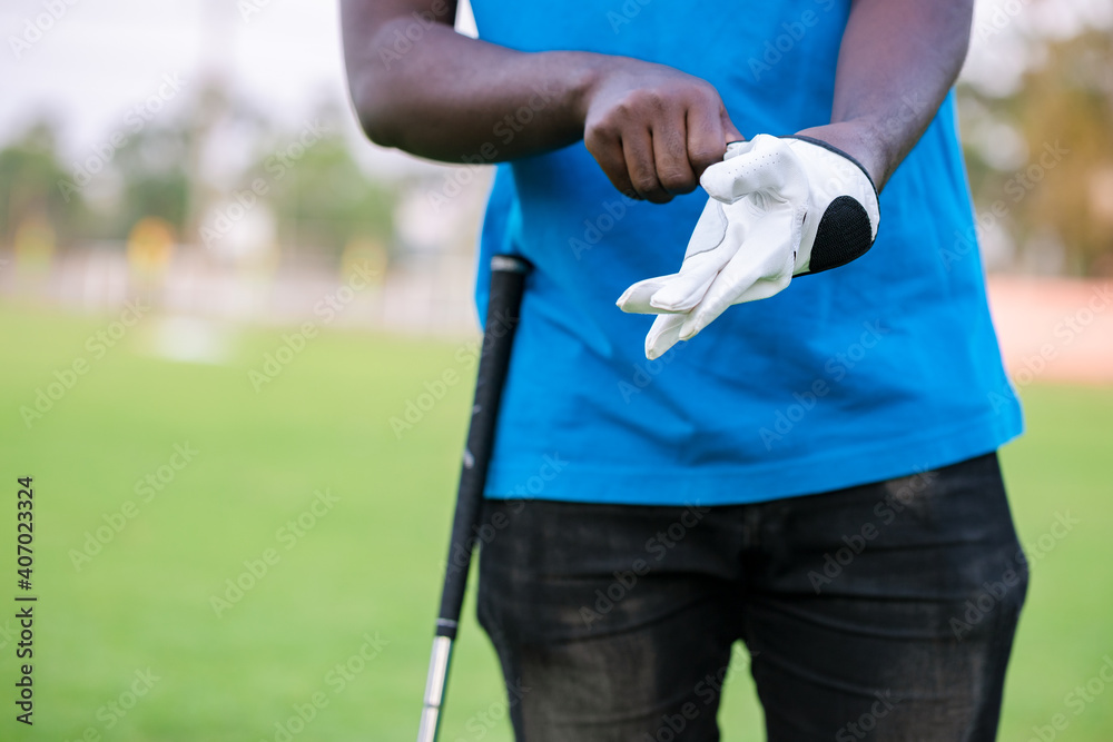 Hand wearing golf glove on tee with club in golf course. Golf helps to relieve tension and stimulate the brain function. Hand wearing golf glove on tee with club in golf course. Golf helps to relieve tension and stimulate the brain function.