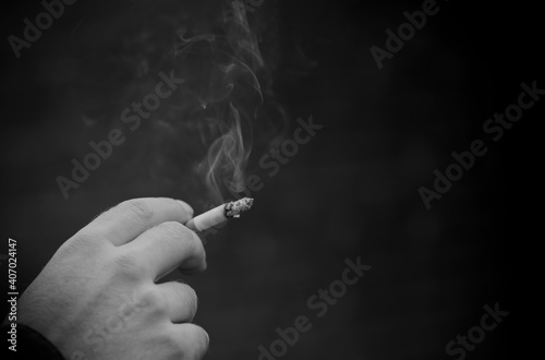 Back and white image of Closeup caucasian man hand holding cigarette with smoke up in the air. men relaxation lifestyle concept