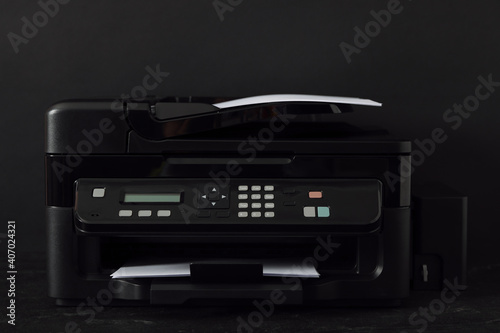 Modern printer with paper on black background