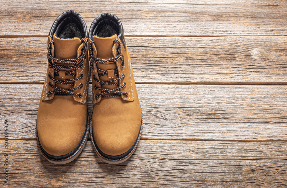 Yellow winter boots on a wooden background.