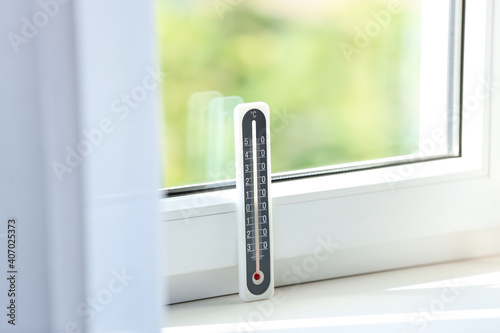 Grey weather thermometer on window sill indoors