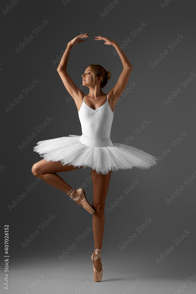 Naklejka premium graceful ballerina in white tutu and pointe shoes on gray background