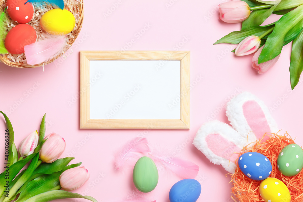 Easter eggs, bunny ears, tulips and frame with copy space on a pink background. Flat lay greeting card.