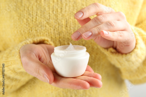 Woman holding jar of moisturizing cream, closeup. Cosmetic product for winter