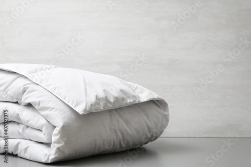 Soft folded blanket on light grey table, closeup. Space for text