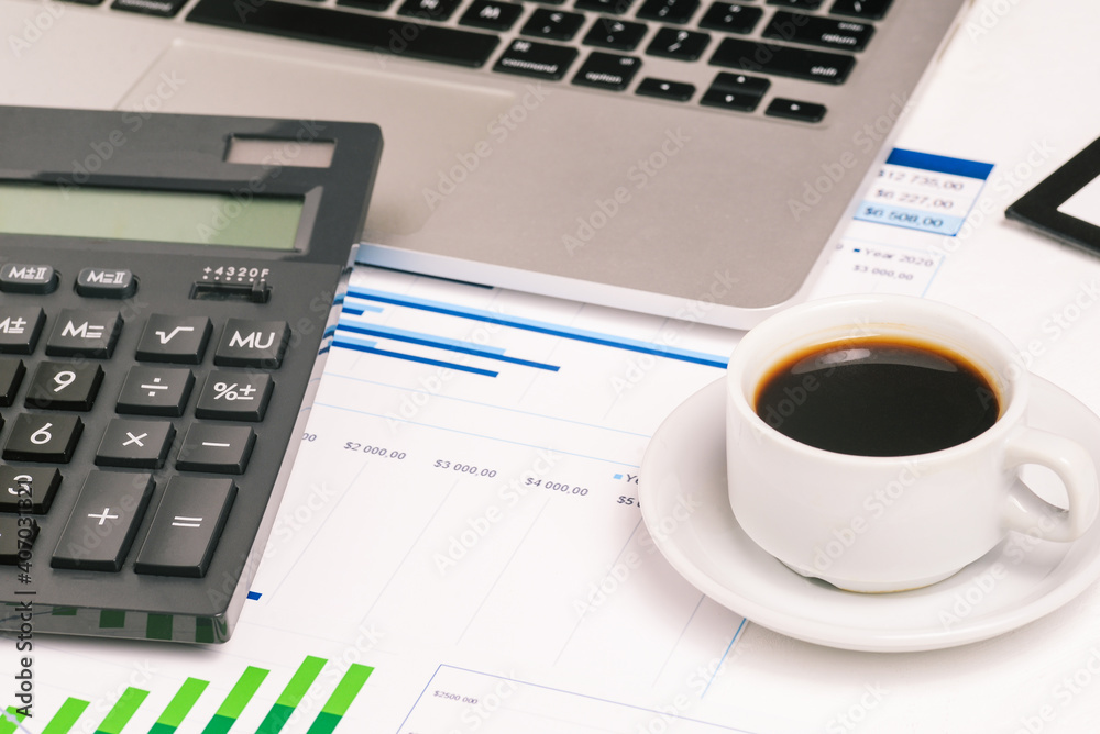 Accounting and analytics. Work desk with a cup of coffee, a computer and diagrams. Budgeting and economics. Tax calculation Accounting and analytics. Work desk with a cup of coffee, a computer and diagrams. Budgeting and economics. Tax calculation