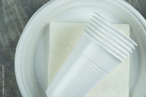 plastic dishes on a concrete background. plastic plates, forks, knives, glasses.