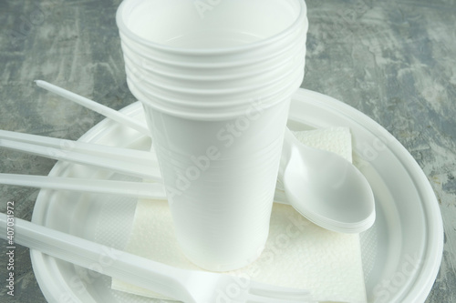 plastic dishes on a concrete background. plastic plates, forks, knives, glasses.