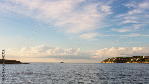 view from the sea to the steep coast with hotels on the Greek island of Crete against the backdrop of a blue cloudy sky