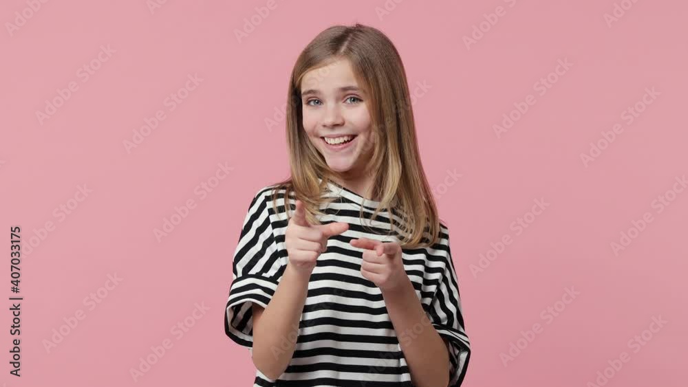 Funny little blonde kid girl 12-13 years old in striped t-shirt isolated on pink background studio. Childhood lifestyle concept. Point fingers camera on you doing phone gesture like says call me back Funny little blonde kid girl 12-13 years old in striped t-shirt isolated on pink background studio. Childhood lifestyle concept. Point fingers camera on you doing phone gesture like says call me back
