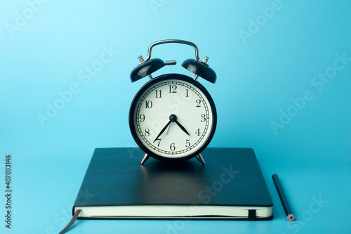 Notepad for sticky notes on desktop with alarm clock. Office desktop, management and timing concept.