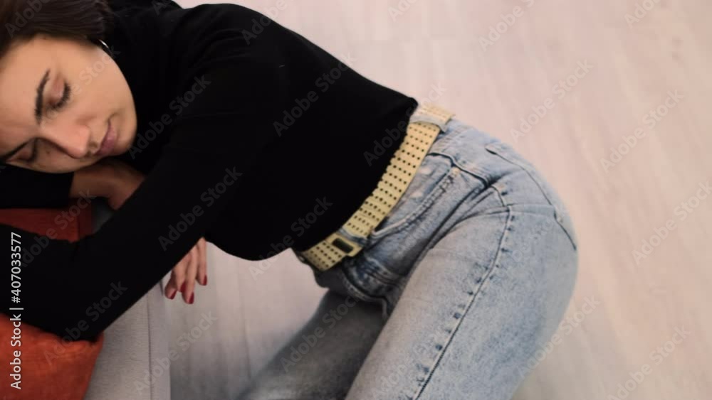 Woman at home in the living room with closed eyes enjoying time alone with herself, resting, sitting on the floor by the sofa Woman at home in the living room with closed eyes enjoying time alone with herself, resting, sitting on the floor by the sofa