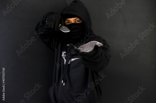 Dangerous man threatening with a knife in the dark street. Robbery concept. Focus on the knife.