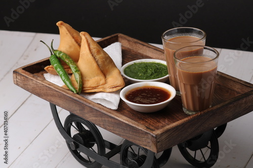 Indian snack Homemade spicy and delicious samosa served with green, tamarind chutney cutting masala tea, chai,  photo