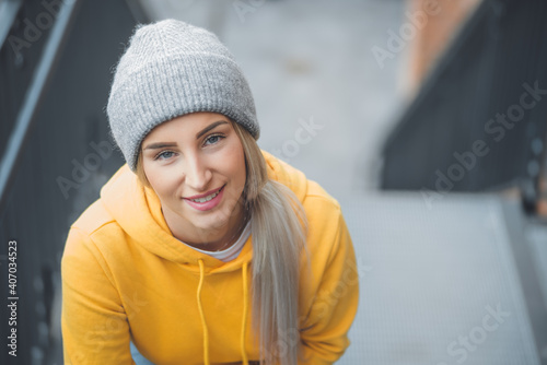 Smiling young beautiful woman looking at camera. Copy space. Outdoors daylight. Half length of pretty girl with positive emotion, smiley expression. Female person wearing casual clothing.