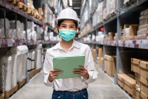 Asian young engineer woman put on face mask to prevent dust pm 2.5 bad air pollution and coronavirus spreading in warehouse.