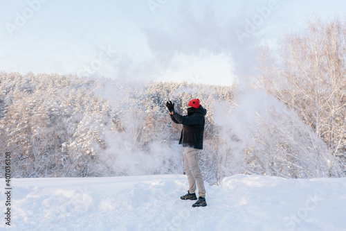 A young man enjoys a winter day on the background of a snow-covered forest