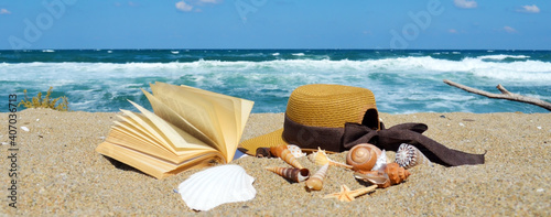 Foto Book with Straw Hat and Seashells at the Summer Beach