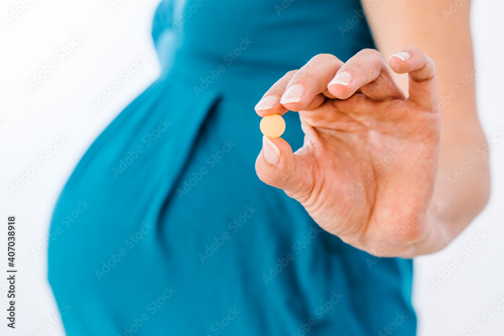 Pregnant woman holding pill in her hand Pregnant woman holding pill in her hand