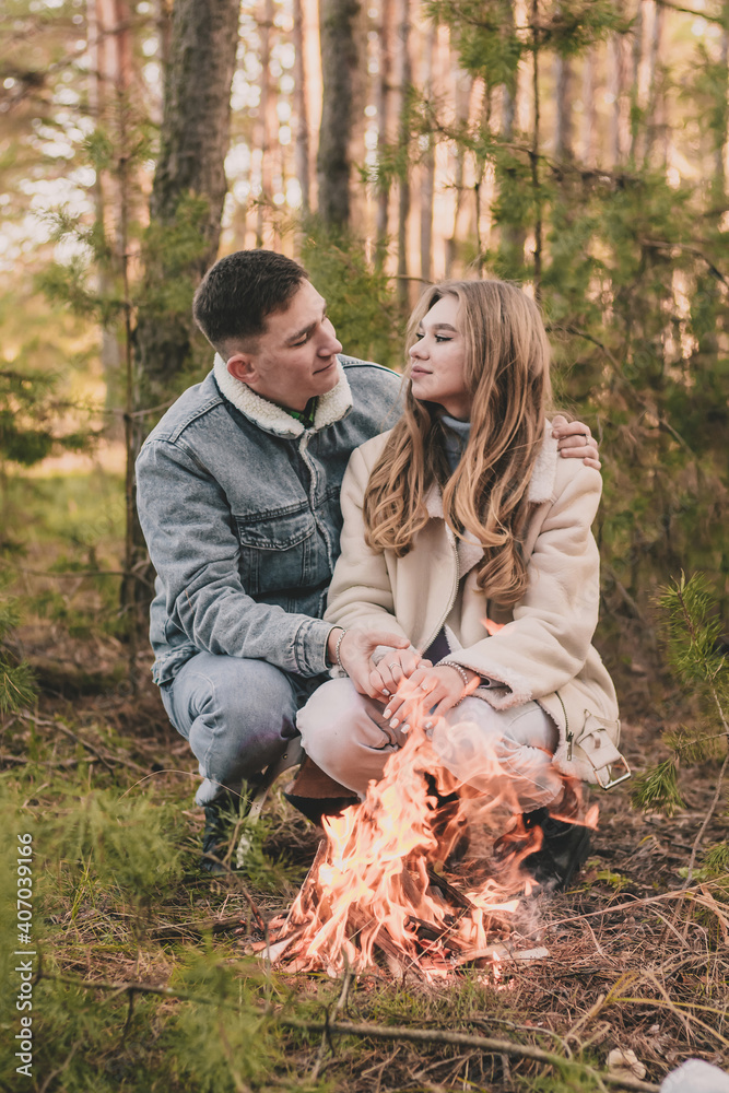couple warms their hands near a fire in a pine forest in winter
couple warms their hands near a fire in a pine forest in winter