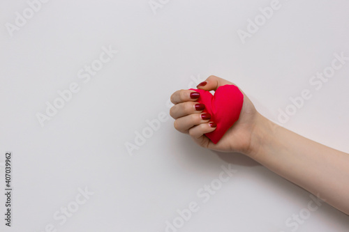 Red heart in the hand of a girl isolated on white background. Valentine's day Symbol. Red heart held tightly in hand representing pure love. Saves a life. Everything is in our hand.