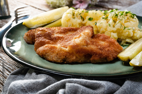 Pork chop served with mashed potatoes and pickled cucumber.
