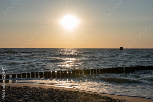 Fototapeta Naklejka Na Ścianę i Meble -  Sunset over the Baltic Sea. Vintage wooden breakwater in the waves. Mielno, Poland. Selective focus. 