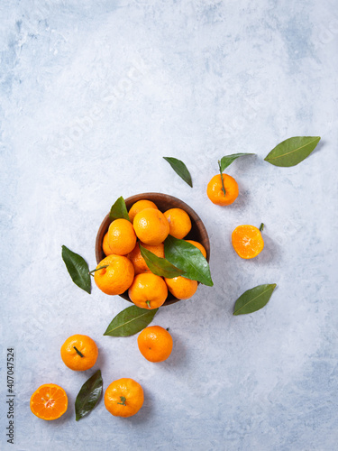 Flat lay sweet and juicy tangerines in a wooden bowl and a few tangerines on a blue background © Kufotos