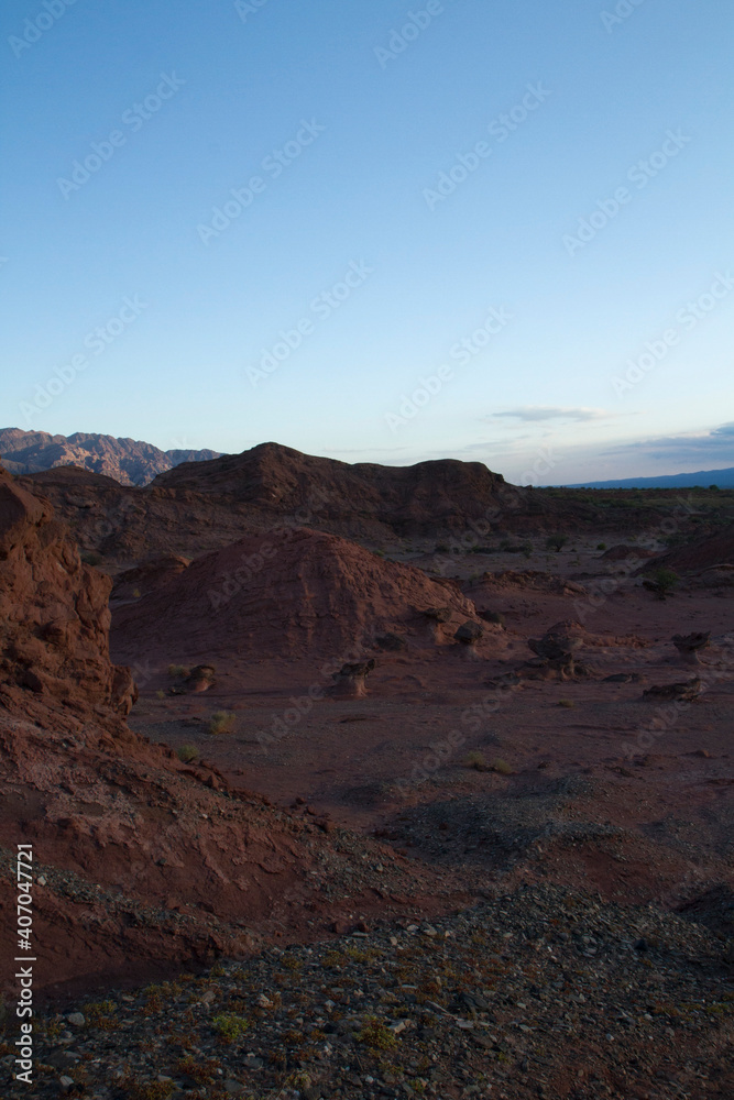 The red canyon and rocky valley at sunset. Panorama view of the arid desert, sandstone formations, and hills in Talampaya national park in La Rioja, Argentina.