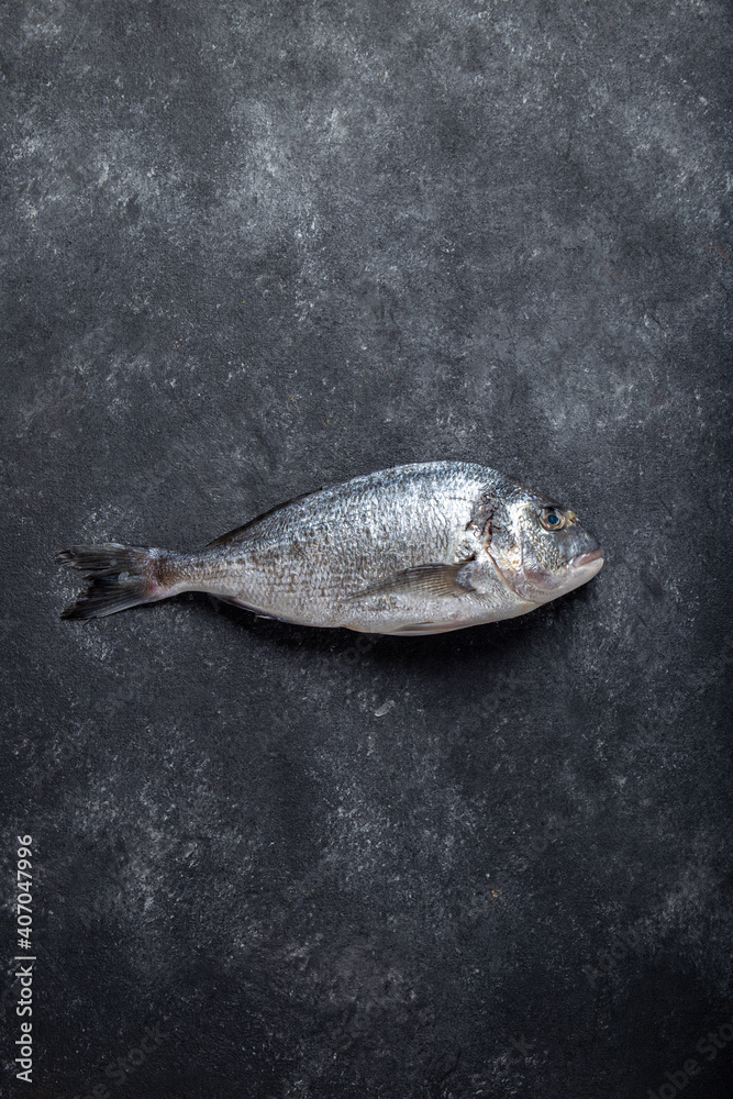 Fototapeta premium Fresh bream fish on dark background. Copy space, top view