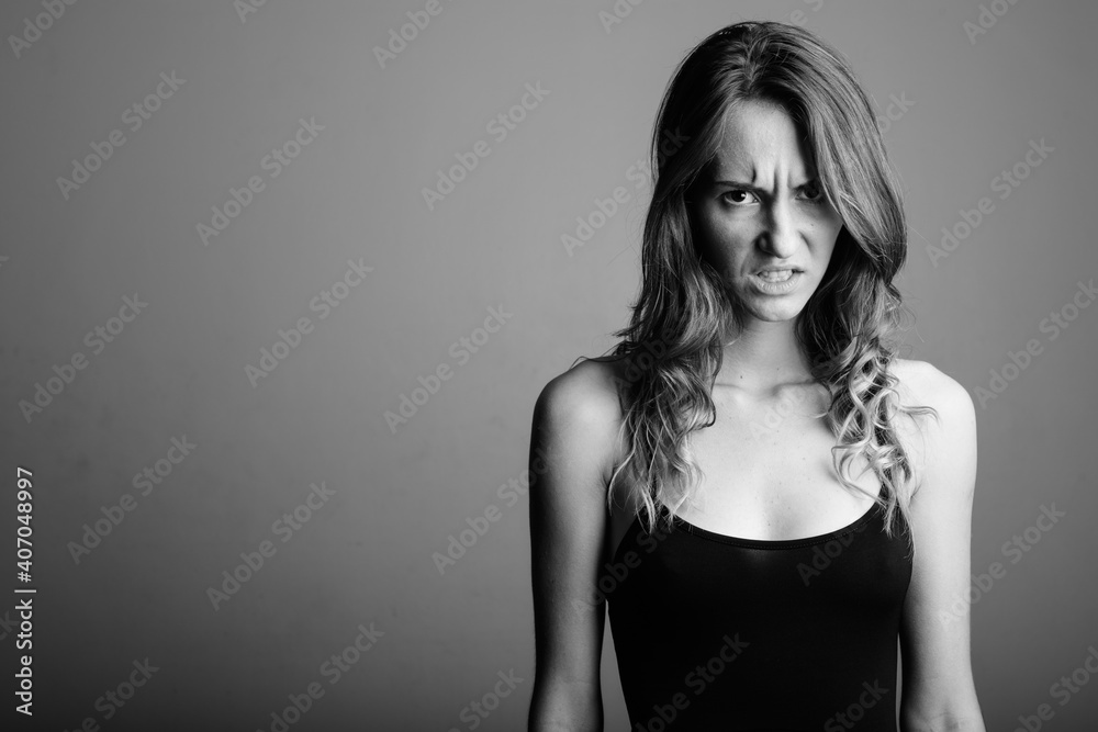 Young beautiful woman wearing sleeveless top against gray background Young beautiful woman wearing sleeveless top against gray background