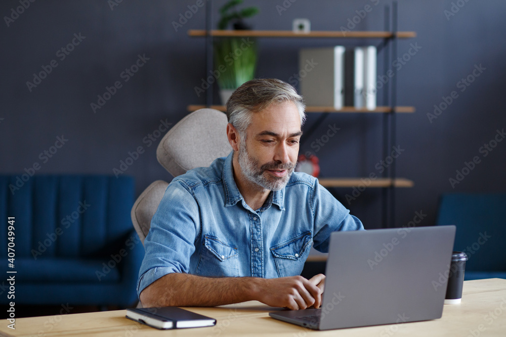 Portrait of grey-haired senior handsome smiling man working from home. Communication online with colleagues and video conference. Online meeting, video call, remote working. Portrait of grey-haired senior handsome smiling man working from home. Communication online with colleagues and video conference. Online meeting, video call, remote working.