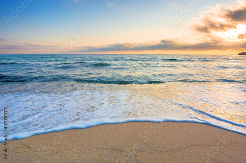 Fototapeta Naklejka Na Ścianę i Meble -  summer vacation at the seaside. beautiful seascape at sunrise. calm waves wash the golden sandy beach. fluffy clouds on the sky