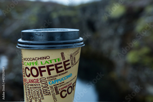 Исландия - 15.03.2018: A glass of hot coffee against the backdrop of the harsh Icelandic landscape. Selective focus. photo