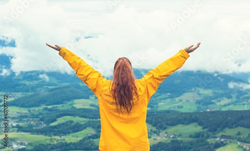 Happy woman standing with arms raised at mountain peak