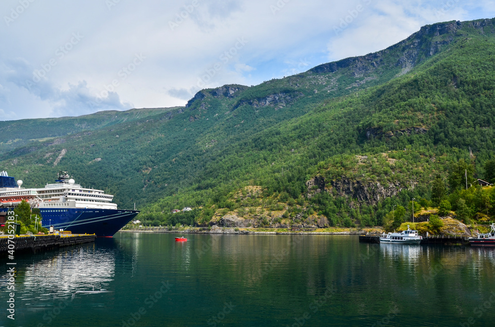 Huge Cruise ship in sea port of Flam. Beautiful landscape with fjords on background. Sognefjord, Norway. Cruise destination and travel.
