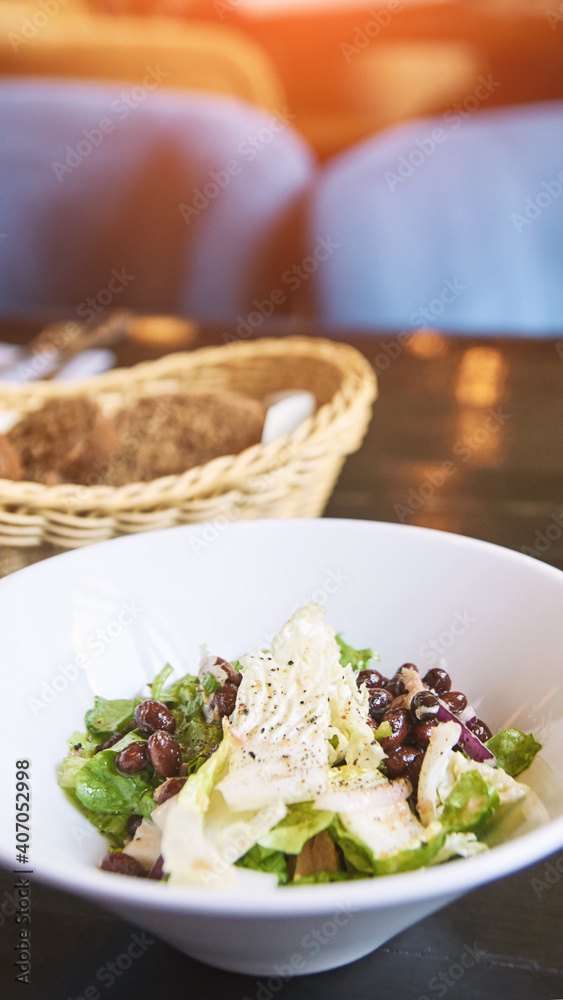 Kidney beans health salad. Dark table and white plate. Cafe menu. Green leaves and cheese fitness dinner. Organic vegetable diet. Black bread bowl. Vegan product. Fast eat.