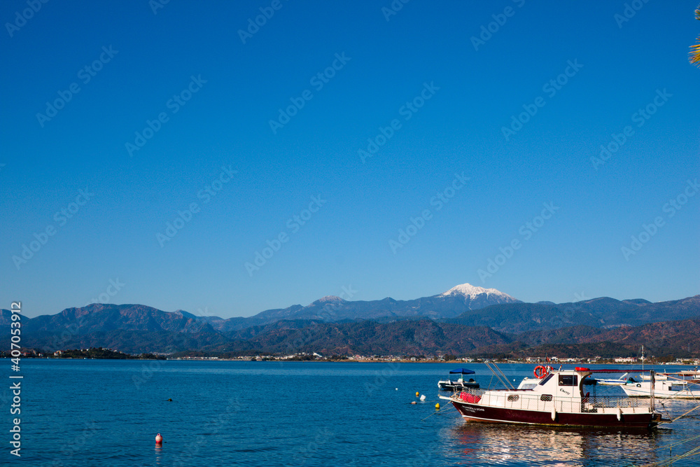 Blue sky, blue sea and small fishing boat on the shore.