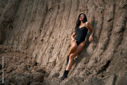 Stunning woman in black bodysuit posing in sand quarry © serhiibobyk